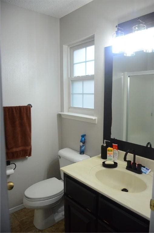 bathroom featuring tile patterned flooring, toilet, vanity, and a textured ceiling