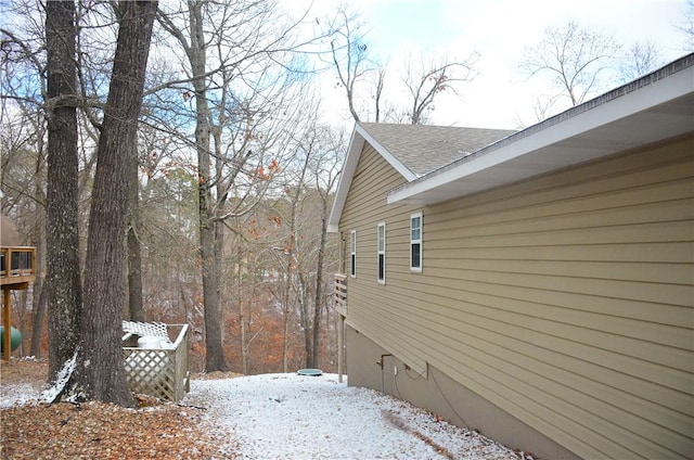 view of snow covered exterior featuring roof with shingles