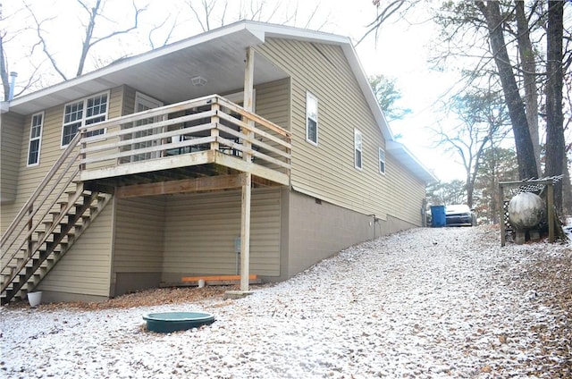 snow covered rear of property featuring stairway and a wooden deck