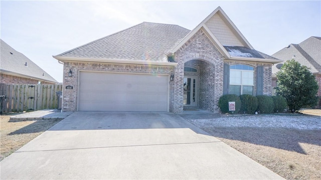 view of front facade with a garage, brick siding, driveway, and roof with shingles