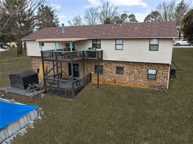 rear view of property featuring a wooden deck, brick siding, and a yard