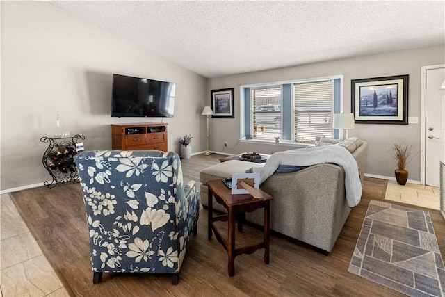 living area featuring baseboards, vaulted ceiling, a textured ceiling, and wood finished floors