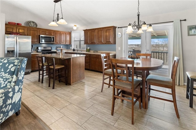 kitchen featuring a breakfast bar area, a kitchen island, appliances with stainless steel finishes, hanging light fixtures, and a notable chandelier