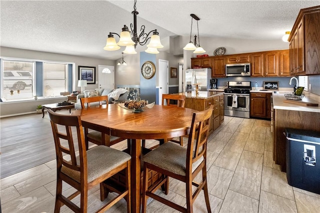 dining area featuring light wood-style floors, lofted ceiling, a textured ceiling, and a notable chandelier