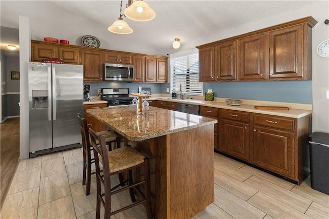 kitchen with pendant lighting, a center island, stainless steel appliances, a breakfast bar area, and lofted ceiling