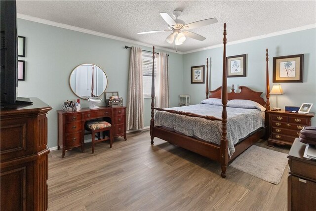 bedroom featuring ceiling fan, ornamental molding, light wood-type flooring, and a textured ceiling