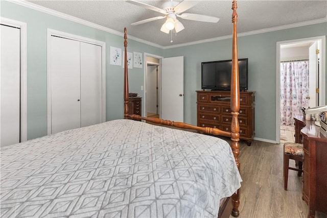 bedroom featuring two closets, ornamental molding, wood finished floors, a textured ceiling, and a ceiling fan