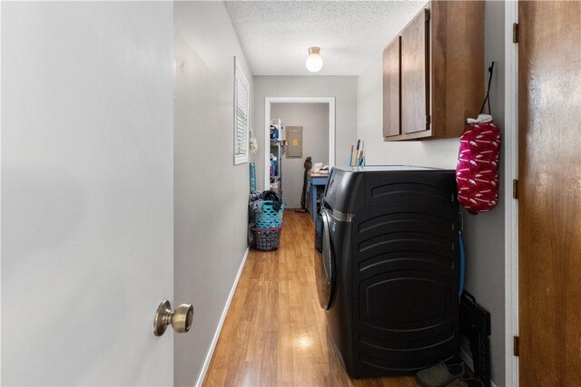 washroom with baseboards, washing machine and dryer, light wood-style floors, cabinet space, and a textured ceiling