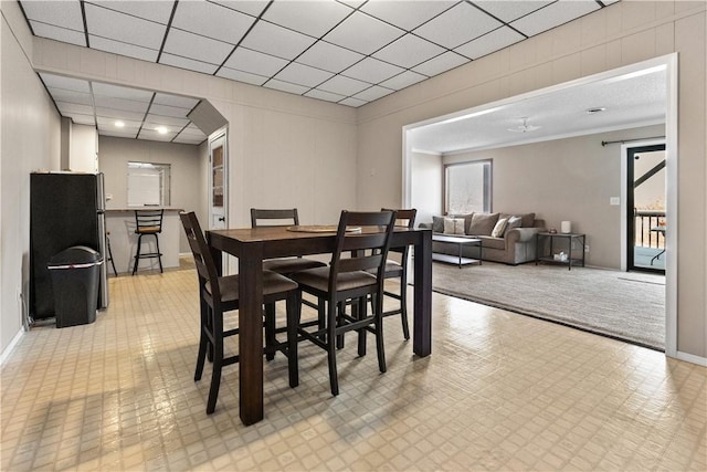 dining area with light floors, baseboards, and a paneled ceiling