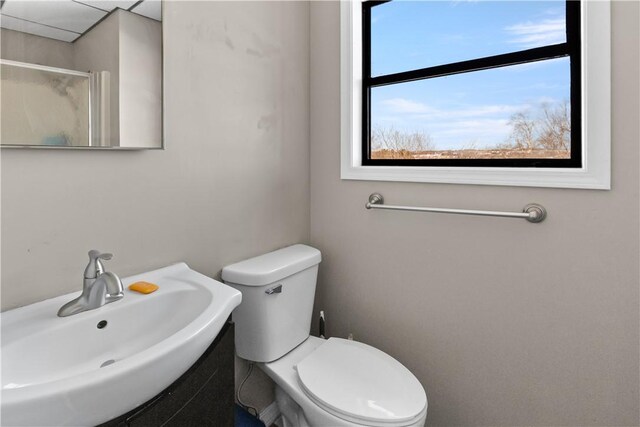 bathroom with toilet, a shower with door, and a sink