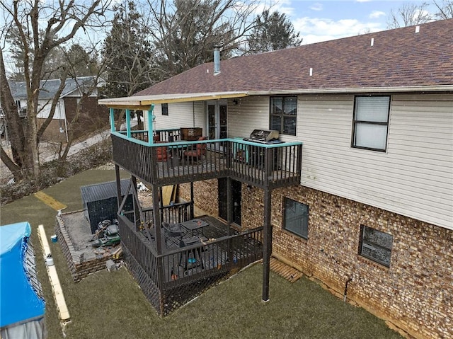 back of property featuring a deck, french doors, brick siding, and roof with shingles