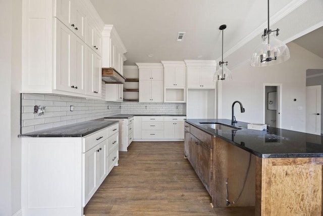 kitchen with a kitchen island with sink, a sink, decorative backsplash, dark wood-type flooring, and visible vents