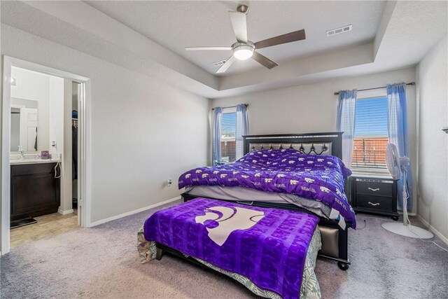 bedroom with a tray ceiling, visible vents, carpet flooring, ceiling fan, and baseboards