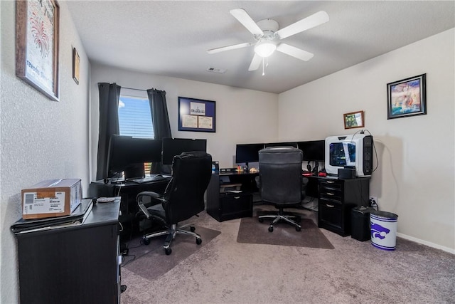 carpeted office space with visible vents, a textured ceiling, a ceiling fan, and baseboards