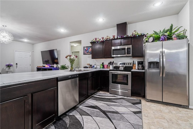 kitchen with stainless steel appliances, dark brown cabinets, pendant lighting, a sink, and recessed lighting