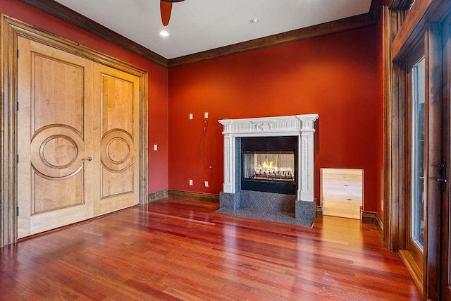 unfurnished living room with crown molding, baseboards, wood finished floors, and a multi sided fireplace