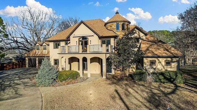 view of front of house with a garage, concrete driveway, a balcony, and stucco siding