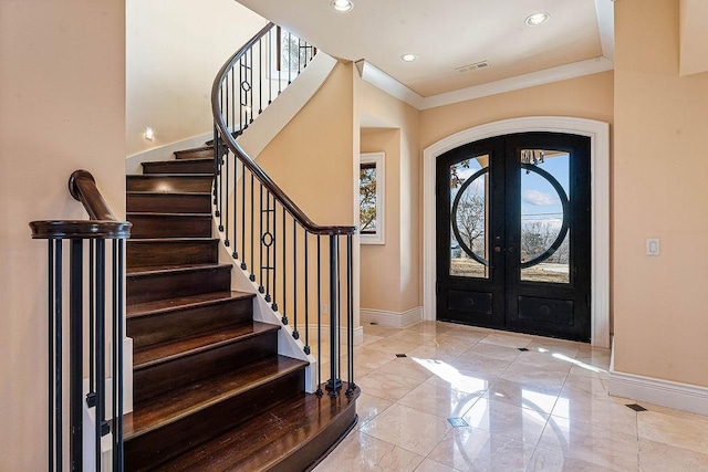 foyer entrance featuring arched walkways, visible vents, baseboards, french doors, and crown molding