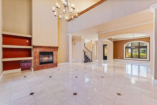 unfurnished living room with a fireplace, a high ceiling, ornamental molding, a chandelier, and baseboards