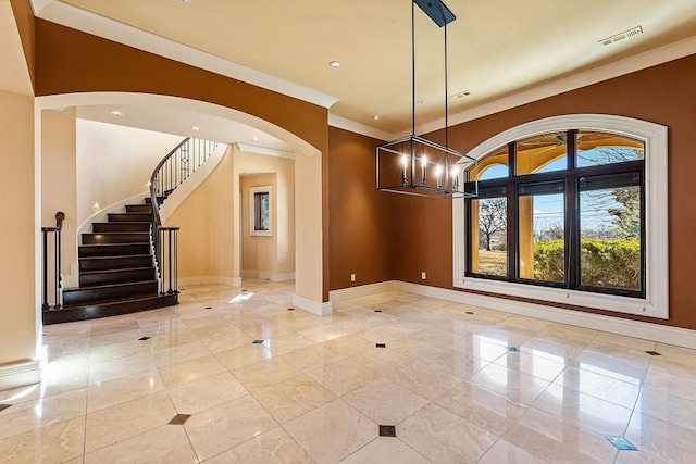 entryway with a notable chandelier, baseboards, arched walkways, and crown molding