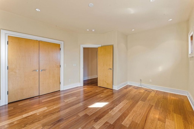 unfurnished bedroom with a closet, baseboards, and wood finished floors