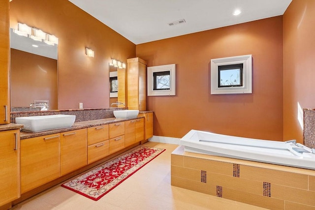 bathroom with double vanity, baseboards, visible vents, and a sink