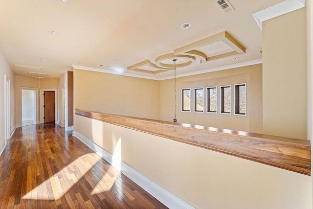 hallway with wood finished floors, visible vents, ornamental molding, a raised ceiling, and attic access