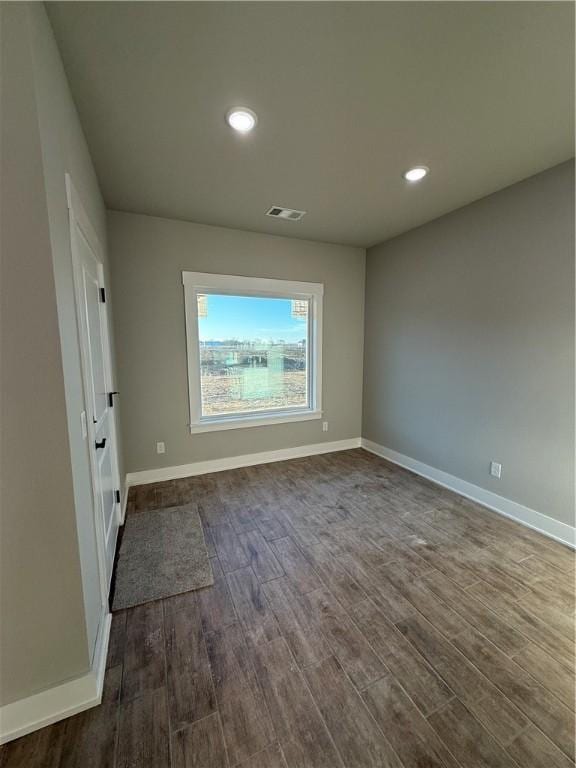 spare room with dark wood-style floors, baseboards, visible vents, and recessed lighting