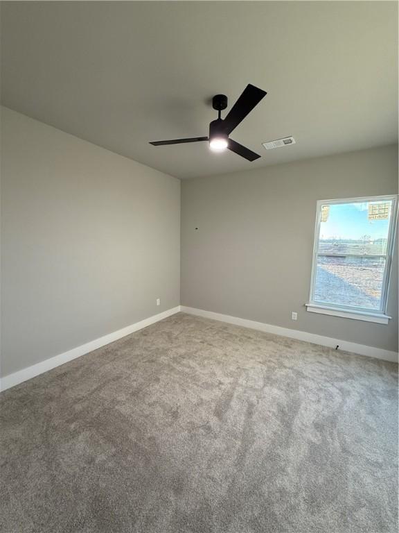 empty room featuring ceiling fan, carpet flooring, visible vents, and baseboards