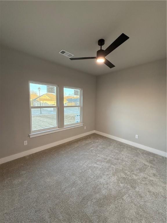 spare room with ceiling fan, carpet floors, visible vents, and baseboards