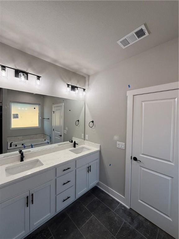 bathroom featuring double vanity, visible vents, a sink, and a bath