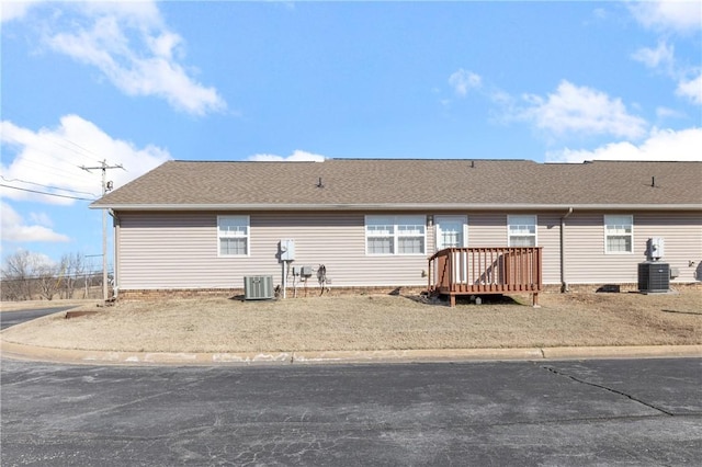 rear view of property featuring a shingled roof, a deck, and central AC unit