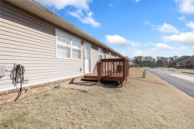 view of side of home featuring a yard and a wooden deck