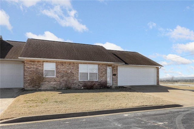 view of front of home with concrete driveway, brick siding, roof with shingles, and an attached garage