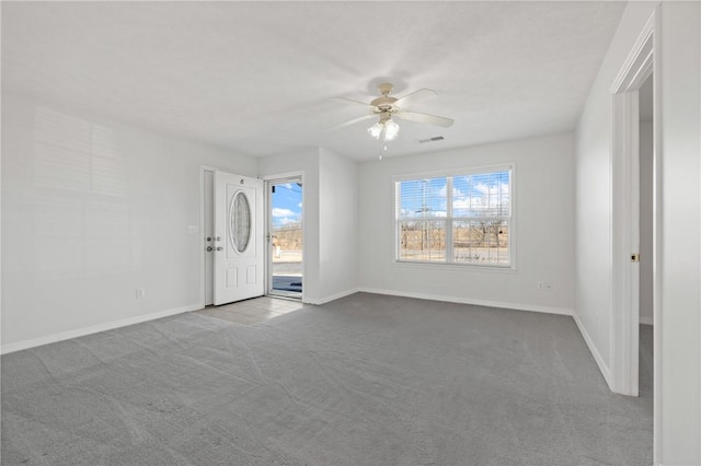 empty room featuring light carpet, a ceiling fan, visible vents, and baseboards