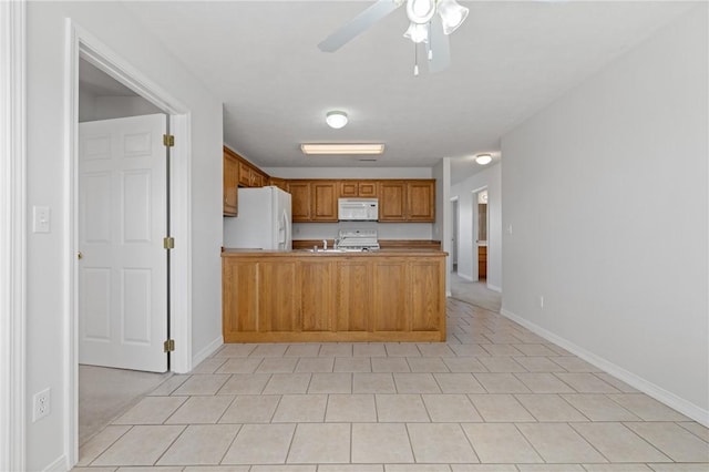 kitchen with a peninsula, white appliances, a ceiling fan, baseboards, and light countertops