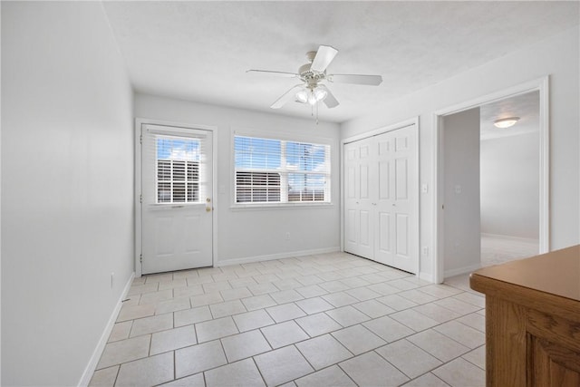 unfurnished bedroom featuring a ceiling fan, a closet, baseboards, and light tile patterned floors