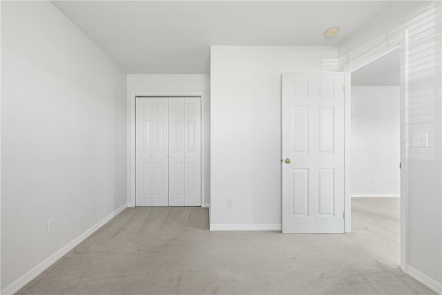 unfurnished bedroom with light carpet, baseboards, and a closet