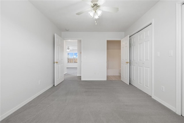 unfurnished bedroom featuring light carpet, a ceiling fan, baseboards, and a closet