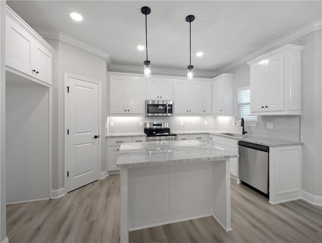 kitchen with light stone counters, stainless steel appliances, a kitchen island, white cabinetry, and pendant lighting