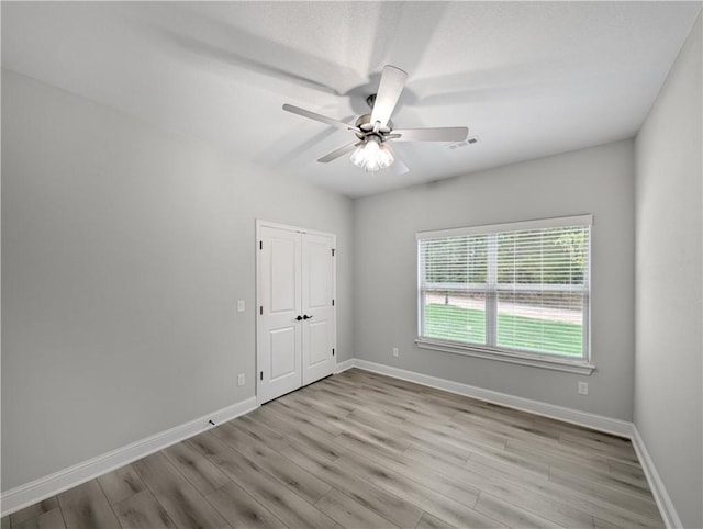 unfurnished room featuring baseboards, ceiling fan, visible vents, and light wood finished floors