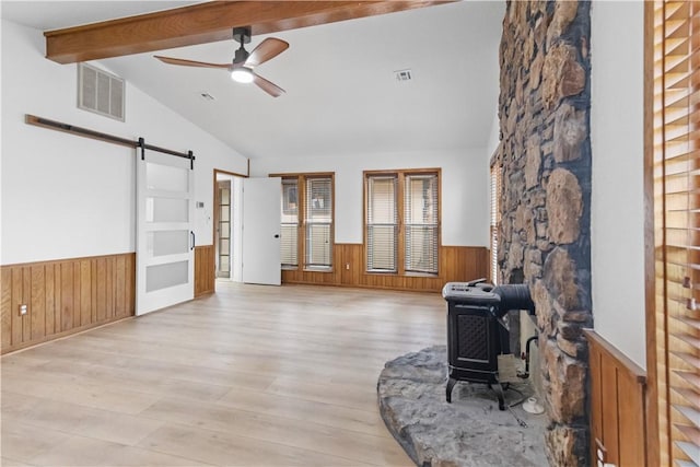 916 S 25th Pl, Rogers, AR 72758 - living area featuring wainscoting, a barn door, wooden walls, ceiling fan, and a wood stove