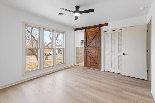 916 S 25th Pl, Rogers, AR 72758 - unfurnished bedroom featuring a barn door, light wood finished floors, a closet, and a ceiling fan