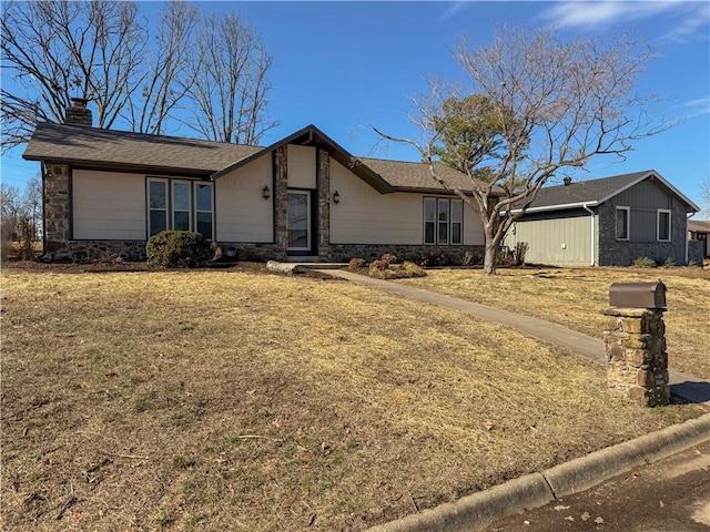 view of front of home featuring stone siding, a chimney, and a front lawn