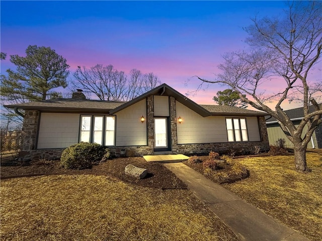 mid-century modern home with stone siding and a chimney