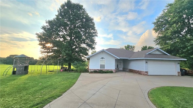 ranch-style home featuring a garage, a shingled roof, concrete driveway, and a front yard