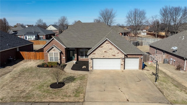 traditional-style home with driveway, roof with shingles, an attached garage, and fence