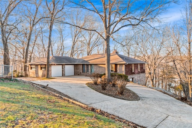 ranch-style house featuring driveway, brick siding, a chimney, and an attached garage