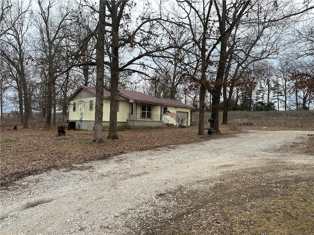 view of front of house with dirt driveway and an attached garage