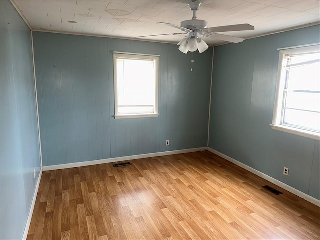 empty room featuring light wood finished floors, visible vents, baseboards, and a ceiling fan